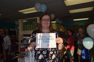 sara karki holding sign that says austin minnesota welcomes you